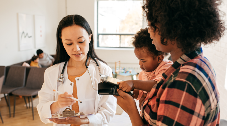 Mom and toddler reviewing paperwork with pediatrician