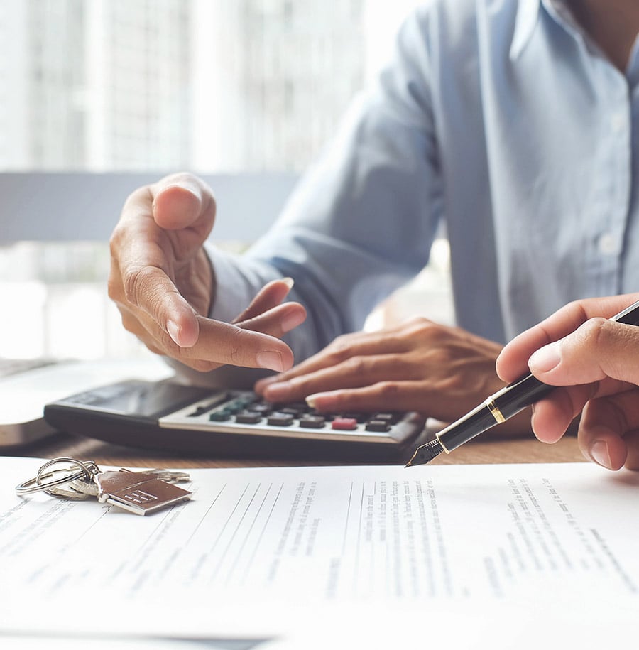 person signing document with keys on desk