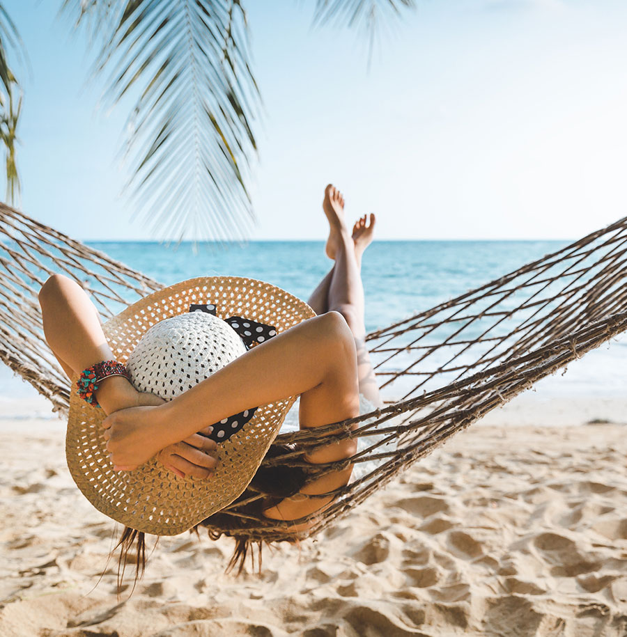 woman with sunhat in a hammock on the beach
